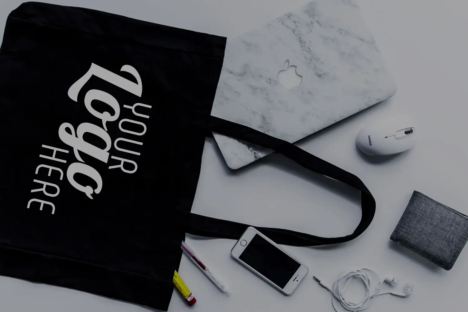 Black promotional tote bag displayed with a laptop and office accessories.
